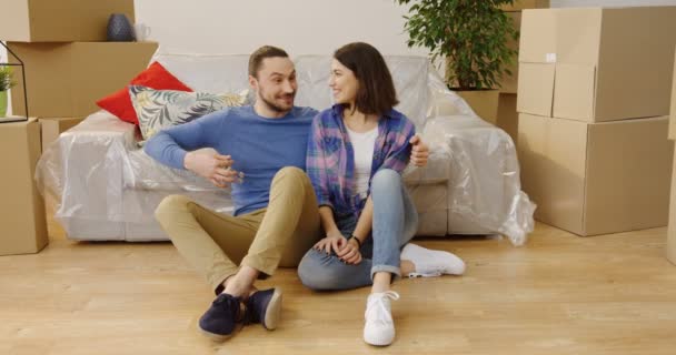 Handsome Caucasian man showing and giving keys from a new apartment to his pretty girlfriend and they having fun among packed boxes. Indoor - Footage, Video