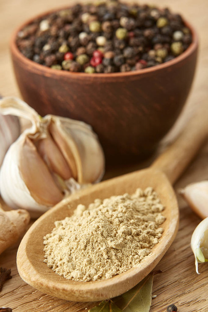 Composition of powder spices on spoon and different sorts of spicies on wooden table background, selective focus - Foto, Bild