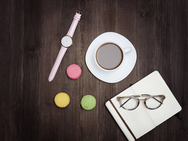 Вид сверху на чашку кофе, макарон, ноутбук, часы и очки
 - Фото, изображение