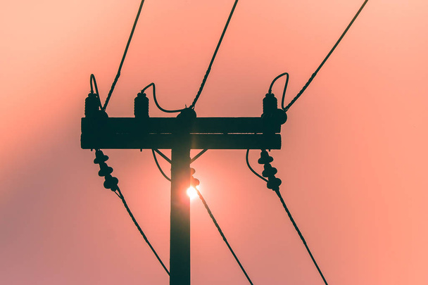 Silhueta de poste de eletricidade e linha de alta tensão com pôr do sol no fundo. (Foco seletivo
) - Foto, Imagem