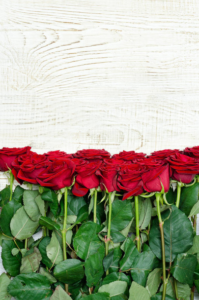 Ramo de rosas escarlata sobre un fondo de madera clara. De cerca.
 - Foto, imagen