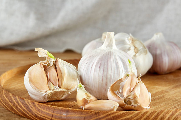 Garlic close up on wooden plate on rustic background, shallow depth of field, selective focus, macro - Foto, immagini