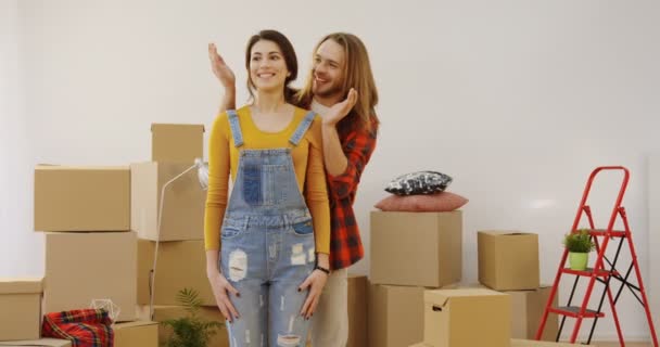 Attractive young man and woman moving in the new house. Man holding his beautiful womans eyes closed and then showing the cozy room and woman being happy with what she seing. Indoors - Footage, Video