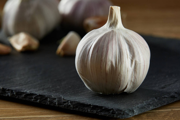 Garlic close up on black piece of board, shallow depth of field, selective focus, macro - Foto, immagini