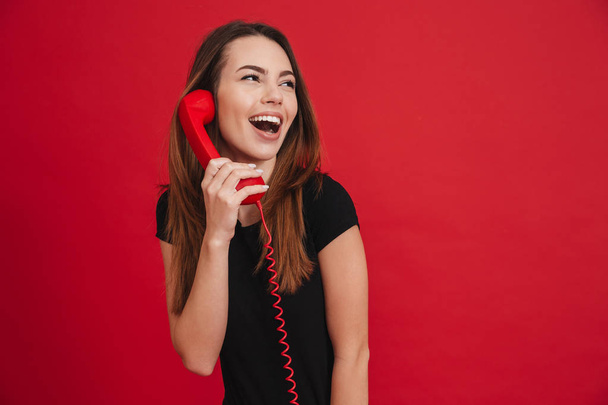 Portrait of a cheerful girl talking on a landline phone - Fotó, kép