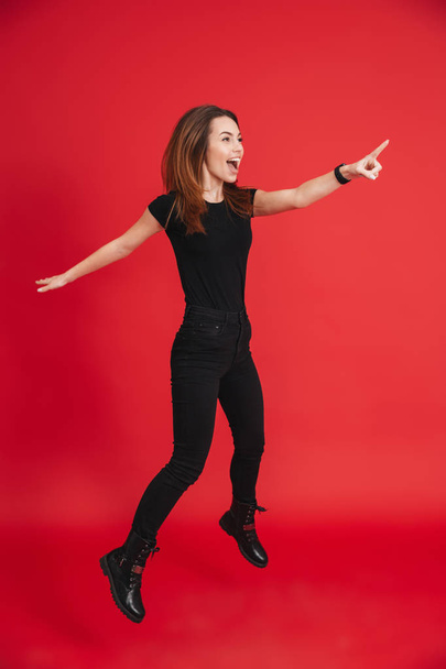 Full-length portrait of positive woman in total black outfit jum - 写真・画像