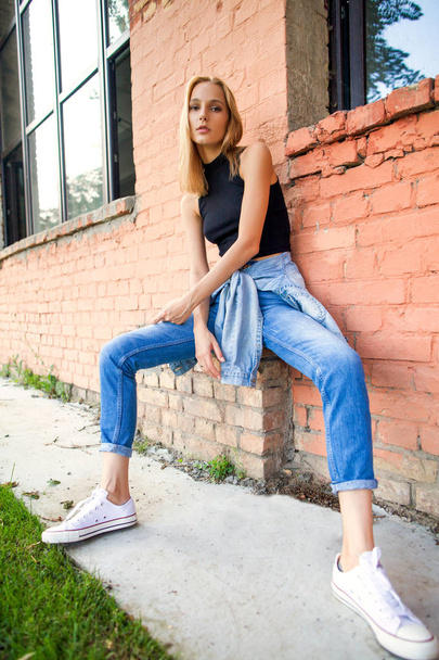fashion girl standing near brick wall in denim and sneakers. Vogue Style - Foto, Bild