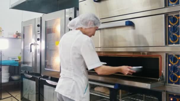 Vrouwelijke bakt op commerciële keuken - vrouw zet bakken in de oven - Video