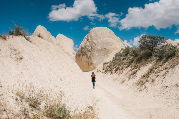 Una chica turística camina a lo largo de la carretera junto a las maravillosas colinas de Capadocia en Turquía y admira la belleza alrededor. El paisaje de Capadocia
. - Foto, Imagen