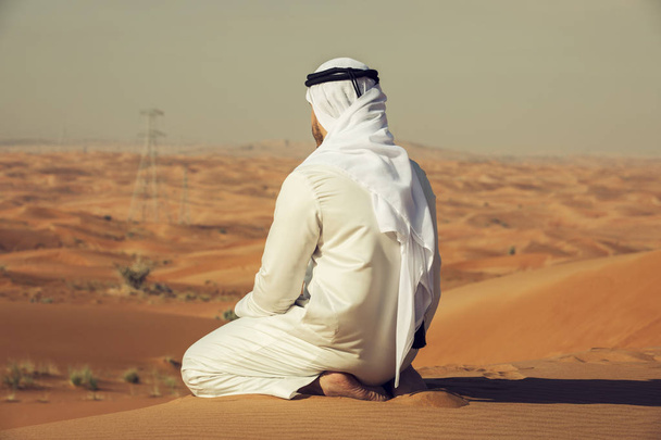 Arabischer Emirat Mann sitzt auf einer Düne in der Wüste von Uae  - Foto, Bild