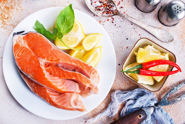 raw salmon and fresh lemon on the plate on table  - Foto, afbeelding