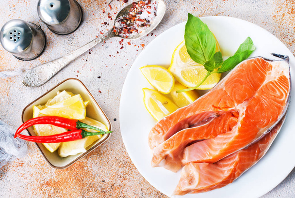 raw salmon and fresh lemon on the plate on table  - Foto, Imagen