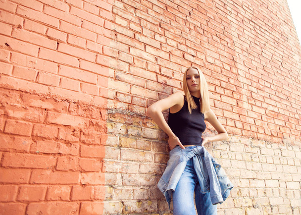 fashion girl standing near brick wall in denim and sneakers. Vogue Style - Photo, image