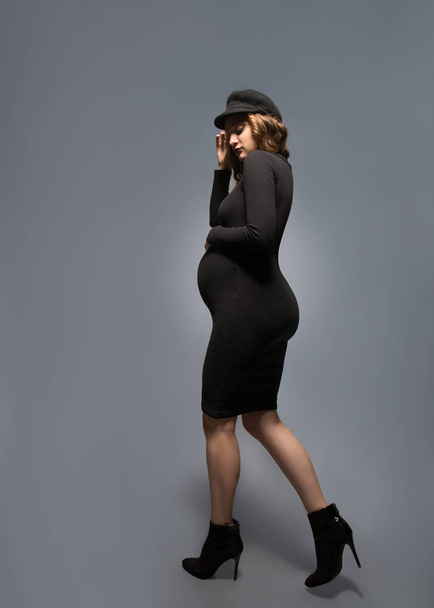 beautiful fashionable girl pregnant in studio stands posing - Foto, afbeelding