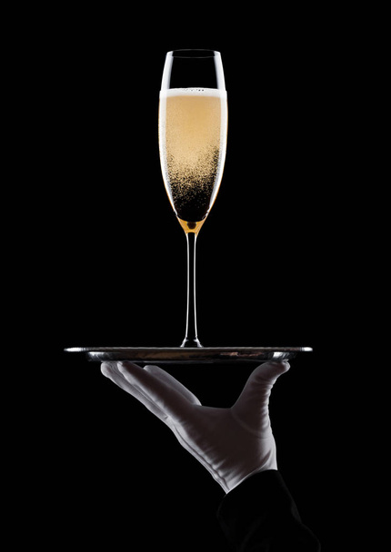 Hand with glove holds tray with champagne glass - Foto, afbeelding
