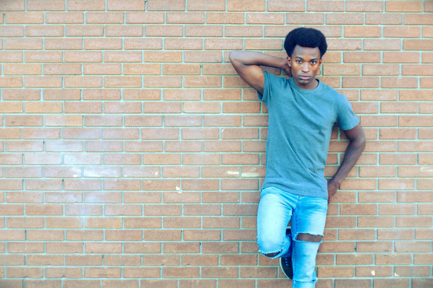 jovem homem de pé posando parede de tijolo fora atitude legal estilo de vida da cidade
  - Foto, Imagem