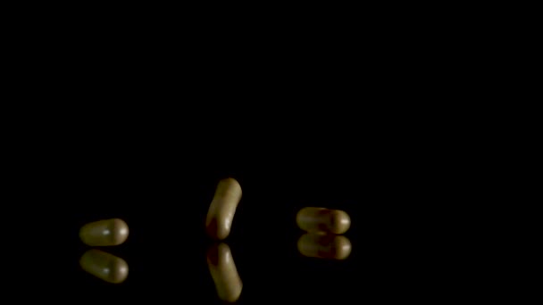 Pill capsules falling on the mirror table. Slowmotion shot, 180 fps - Felvétel, videó