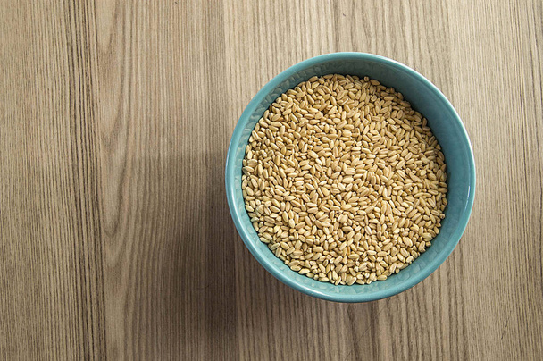 зерна білої пшениці на дерев'яній підлозі і в тарілці, очищені зерна пшениці
,  - Фото, зображення