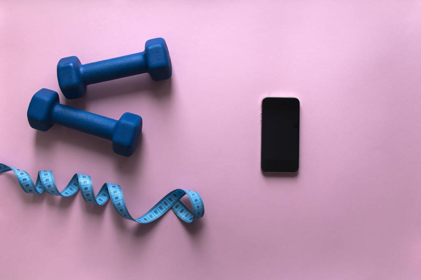 on a pink background dumbbells blue color tape centimeter phone smartphone  - Photo, Image