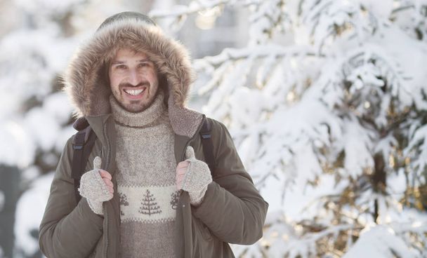 Handsome smiling man in winter snow - Fotoğraf, Görsel