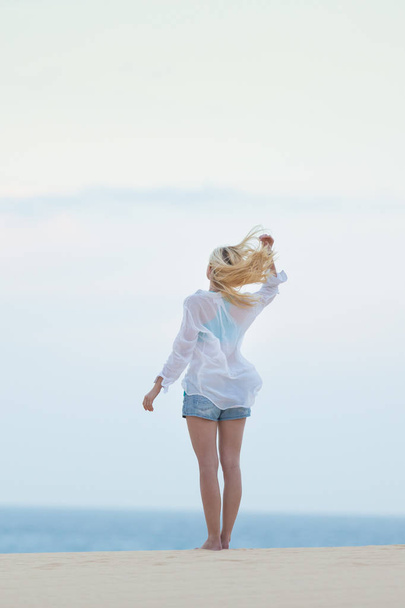 Woman on sandy beach in white shirt. - Zdjęcie, obraz