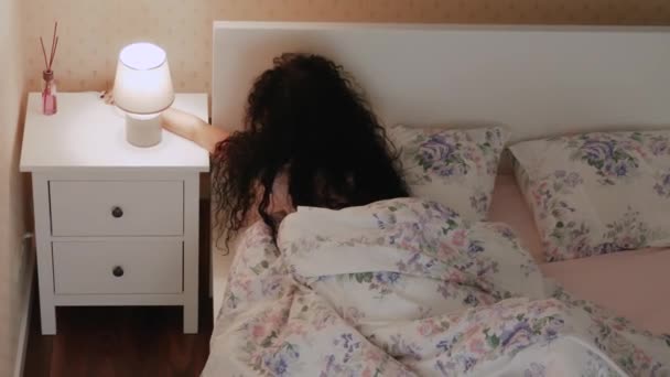 Frau bereitet sich vor, ins Bett zu gehen und zu schlafen und schaltet den Nachttisch neben dem Bett aus - Filmmaterial, Video