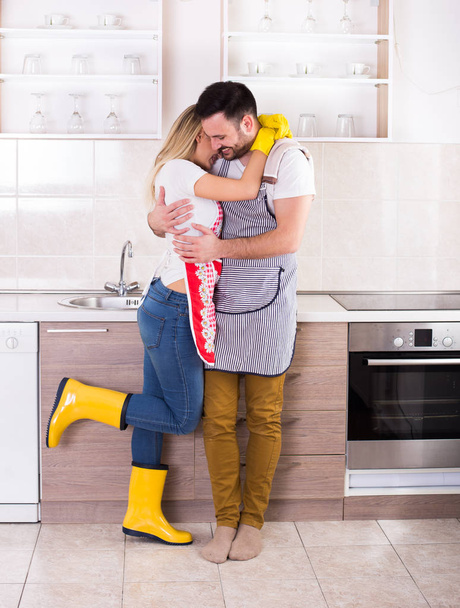Pareja joven abrazándose después de las tareas domésticas
 - Foto, Imagen