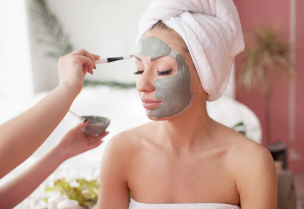 Spa teen girl applying facial clay mask. Beauty treatments. - Photo, Image