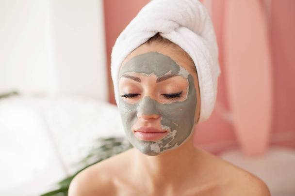 Spa teen girl applying facial clay mask. Beauty treatments. - Valokuva, kuva