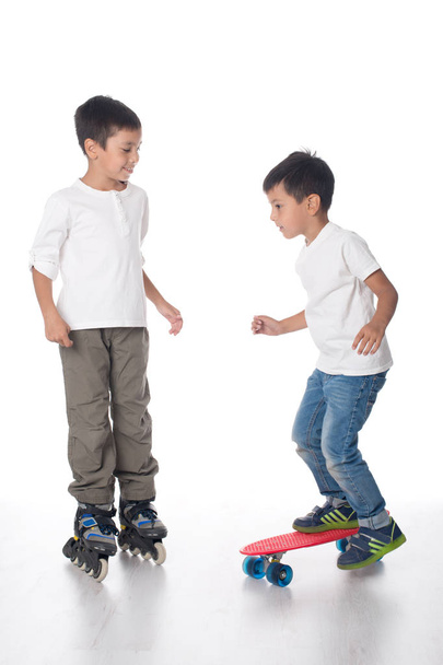 Two boys ride roller skates and a board. - Valokuva, kuva