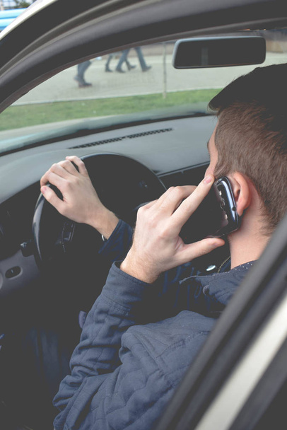 Όμορφος άνδρας χρησιμοποιώντας smartphone κατά την οδήγηση του αυτοκινήτου - Φωτογραφία, εικόνα