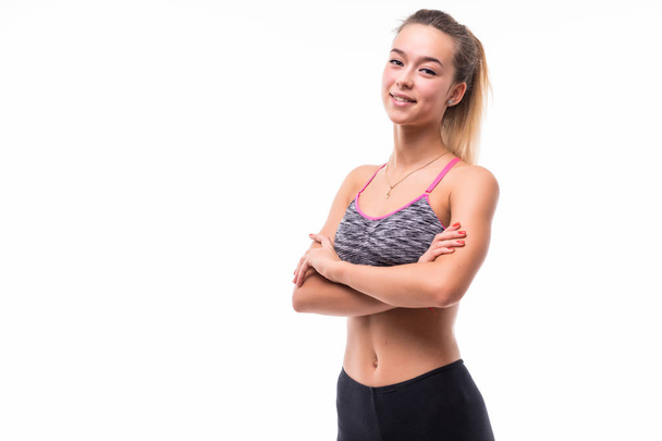 Photo of cheerful young sports woman standing isolated over white background looking camera with arms crossed. - Fotoğraf, Görsel