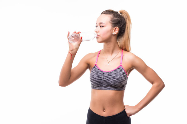 Young woman in fitness wear drinking iolated over white - Valokuva, kuva