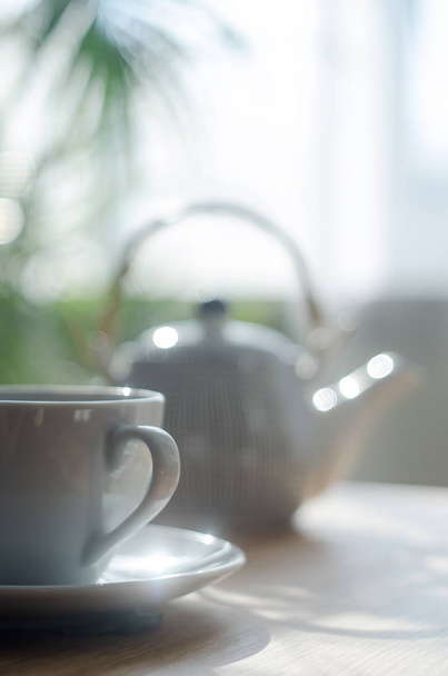 weiße Tasse Tee mit Teekanne auf dem Tisch im Tageslicht  - Foto, Bild