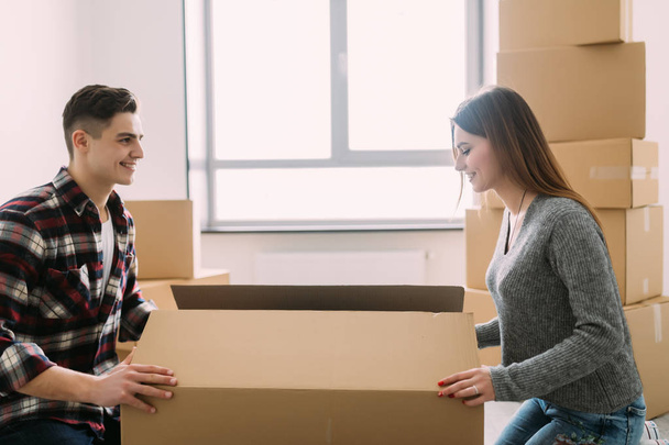 Souriant jeune couple déballer des boîtes en carton dans une nouvelle maison
 - Photo, image