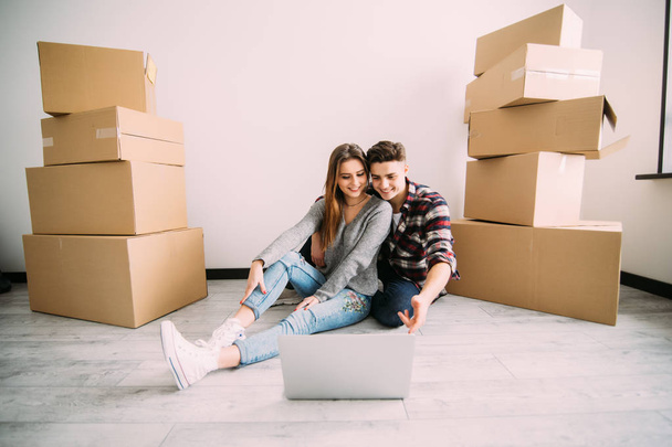Boldog fiatal pár keres apartmanok laptop. Mozgó, új lakás vásárlása. - Fotó, kép