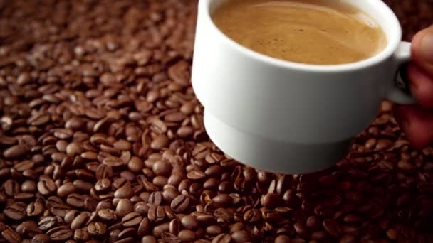 Widok z boku biały filiżanka czarnej kawy na ziarna kawy - Materiał filmowy, wideo
