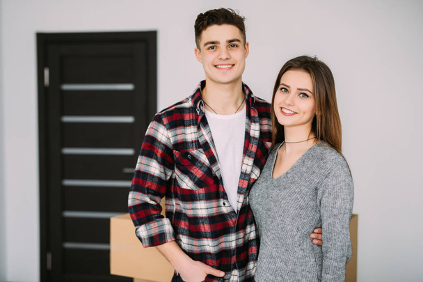 Usmívající se pár opírající se o boxy v novém domově. Mladý pár přestěhoval do nového bytu společně přemístění - Fotografie, Obrázek