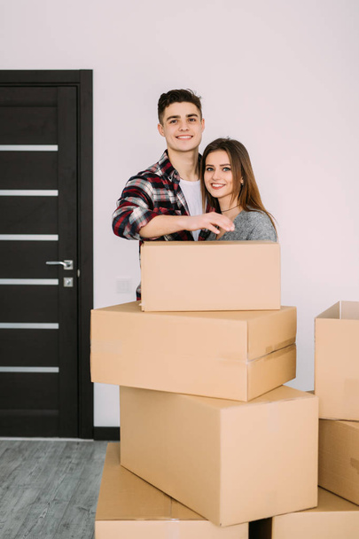 Smiling couple leaning on boxes in new home. Couple in new apparment after moving. - Fotoğraf, Görsel