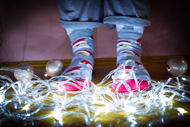 Patas de niña en calcetines de invierno de temporada con decoración navideña. Calcetines divertidos de Navidad. Lindos calcetines de Navidad con decoración en invierno
 - Foto, Imagen