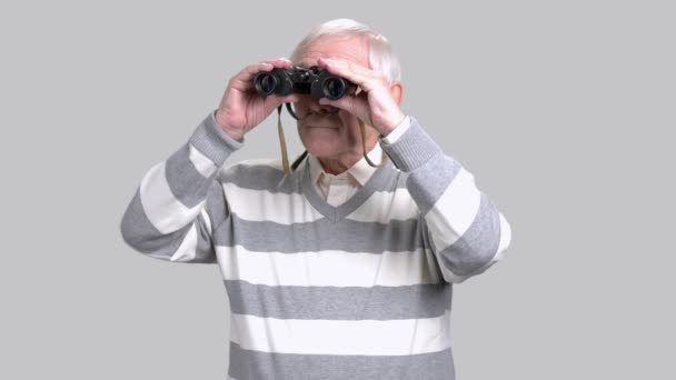 Anciano con prismáticos, fondo gris
. - Metraje, vídeo