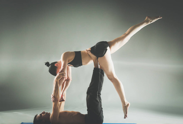 Young couple practicing acro yoga on mat in studio together. Acroyoga. Couple yoga. Partner yoga. - Foto, Imagen