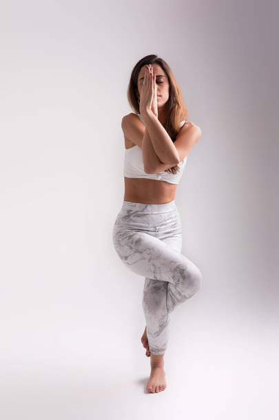 Sportowy młoda kobieta robi praktyki jogi na tle białego studia, pojęcie zdrowego życia i naturalną równowagę między ciałem i rozwój umysłowy - Zdjęcie, obraz