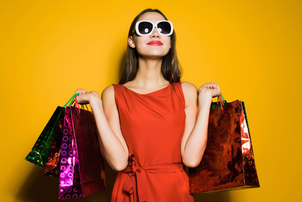 happy young girl shopaholic in red dress and sunglasses bought many gifts on a black Friday - Photo, image