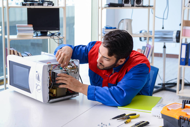 Young repairman fixing and repairing microwave oven - Photo, Image