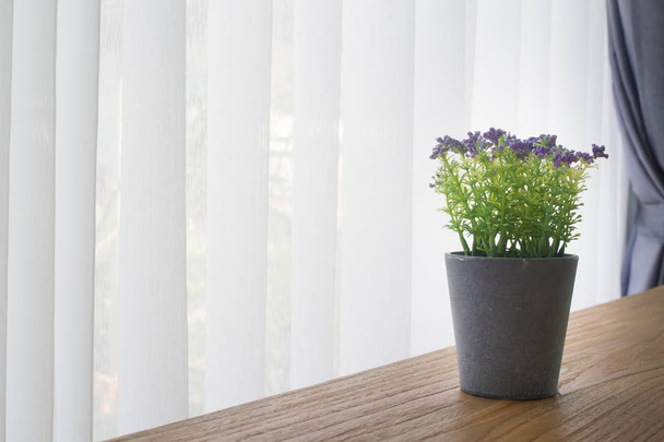 mesa de oficina de madera con maceta violeta en el viento de la cortina blanca
 - Foto, Imagen