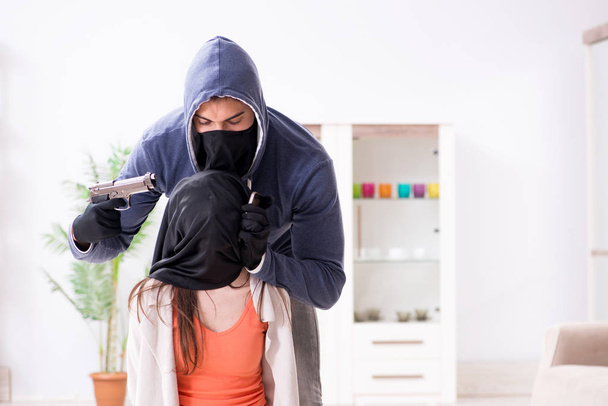 Silahlı bir adam evde genç bir kadına saldırıyor. - Fotoğraf, Görsel