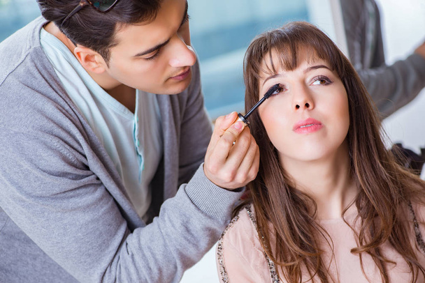 man doet make-up voor schattig vrouw in schoonheid salon - Foto, afbeelding