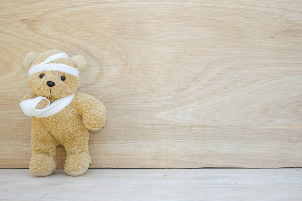 Urso de pelúcia com ligaduras e mão quebrada no fundo de madeira, cópia
 - Foto, Imagem