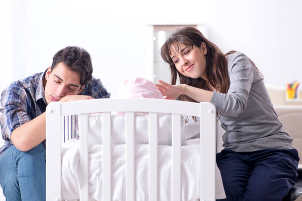 Молоді батьки зі своєю новонародженою дитиною біля ліжка
 - Фото, зображення